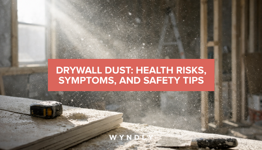 A photorealistic photograph of drywall dust particles floating in the air at a construction site, with visible dust settling on surfaces and sunlight streaming through to highlight the particles.